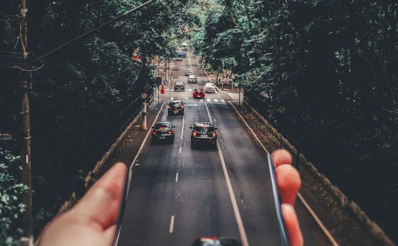 forced perspective photography of cars running on road below smartphone